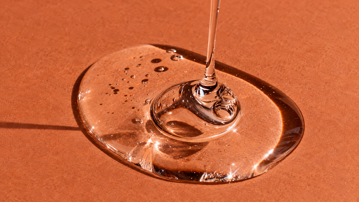 A pool of clear serum on a terracotta surface, the texture of snail secretion filtrate in skincare